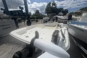 Slide: The Image of 2022 Mako Pro Skiff 15 CC boat docked under a cloudy sky. - 2