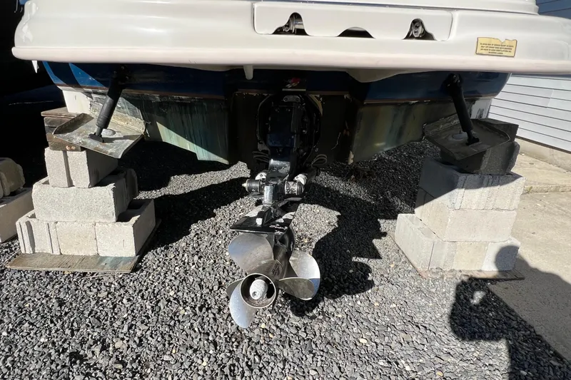 Slide: The Image of 2004 Sea Ray 240 Sundeck boat on cinder blocks, showing propeller and hull. - 3