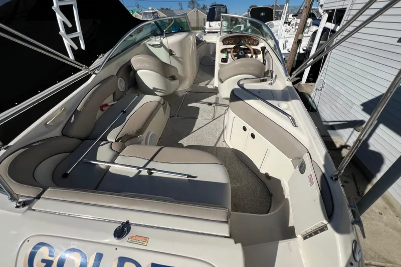 Slide: The Image of 2004 Sea Ray 240 Sundeck boat interior with beige seating and steering console. - 4