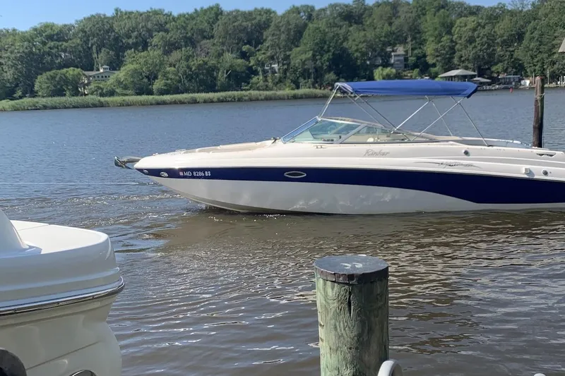 Slide: The Image of 2004 Rinker 282 Captiva Bowrider on a calm river with lush green trees. - 2