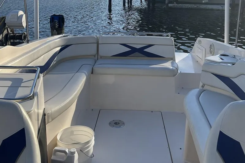Slide: The Image of 2004 Rinker 282 Captiva Bowrider interior with white and blue seating, docked by the water. - 7