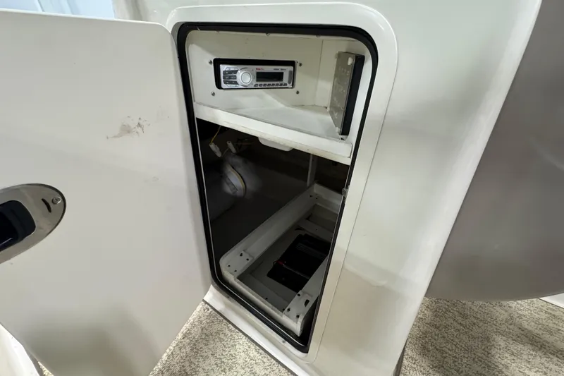 Slide: The Image of Open storage compartment in 2004 Sea Ray 200 Sundeck boat, featuring a stereo system. - 19