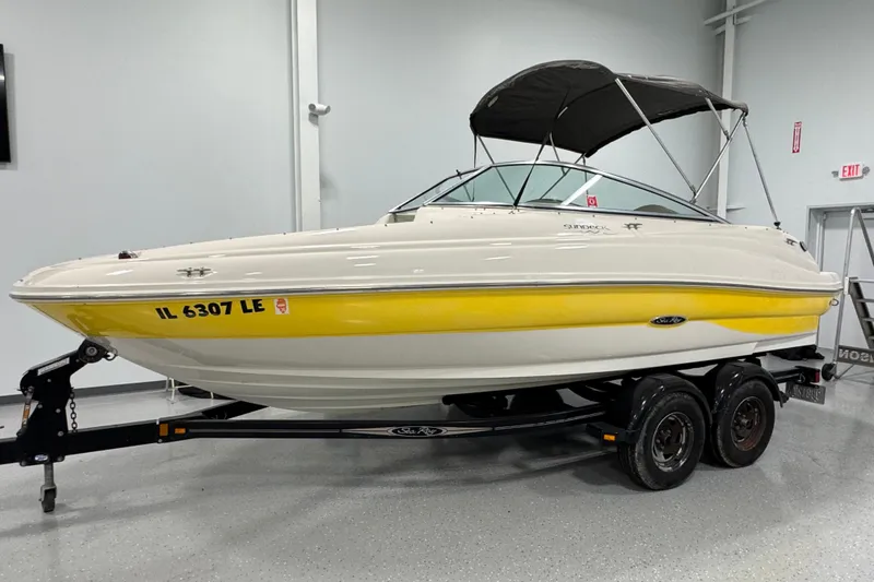 Slide: The Image of 2004 Sea Ray 200 Sundeck boat with yellow hull on trailer, indoor setting. - 3