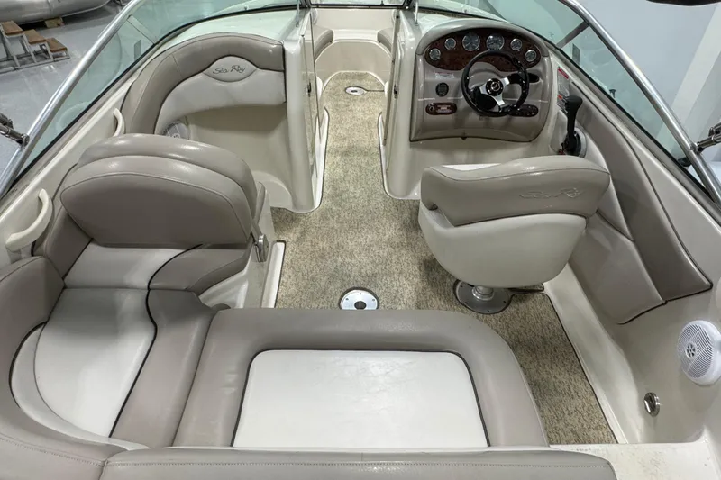 Slide: The Image of 2004 Sea Ray 200 Sundeck interior with beige seating and steering console. - 6