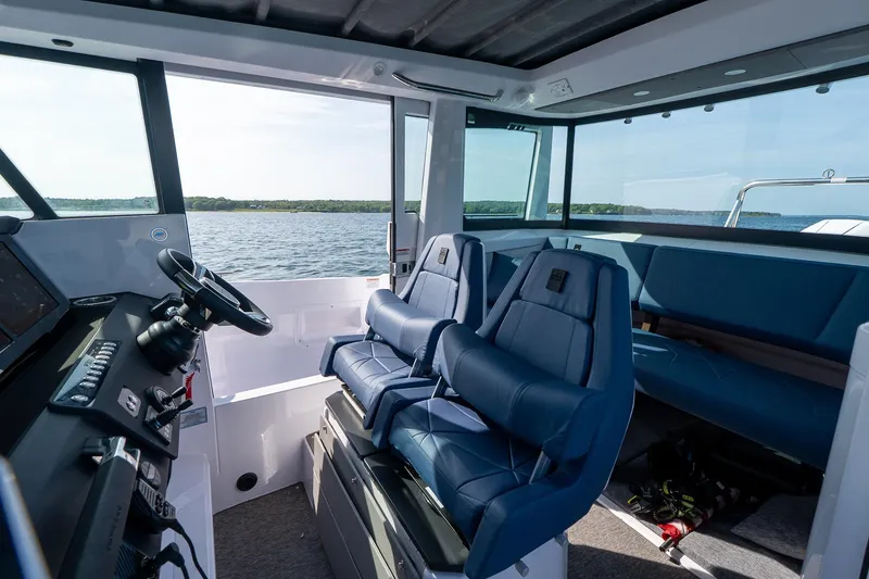 Slide: The Image of Interior of 2026 Axopar 29 Cross Cabin boat with blue seating and steering console. - 23