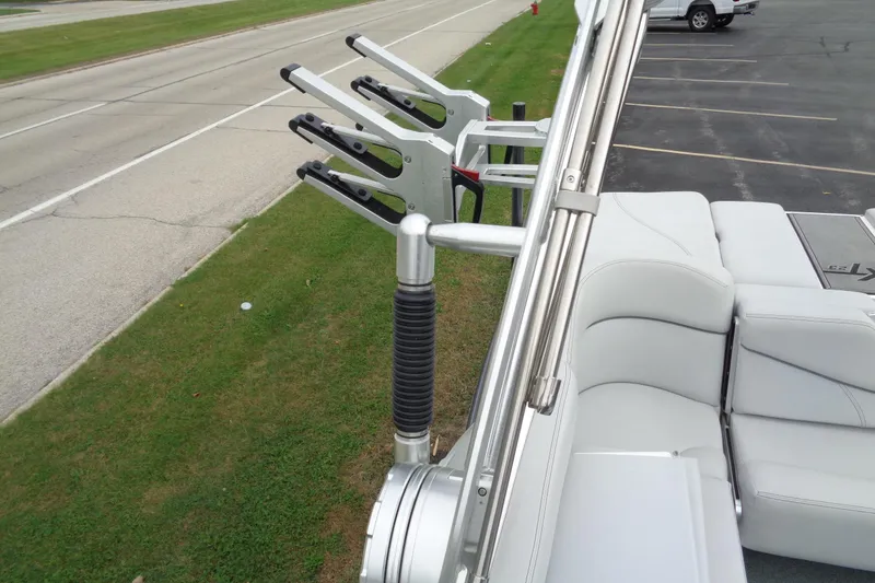 Slide: The Image of 2020 MasterCraft XT23 boat with wakeboard racks and cushioned seating, parked near a road. - 37