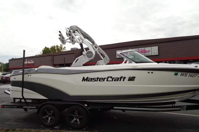 Slide: The Image of 2020 MasterCraft XT23 boat on trailer, parked outside a marine dealership. - 56