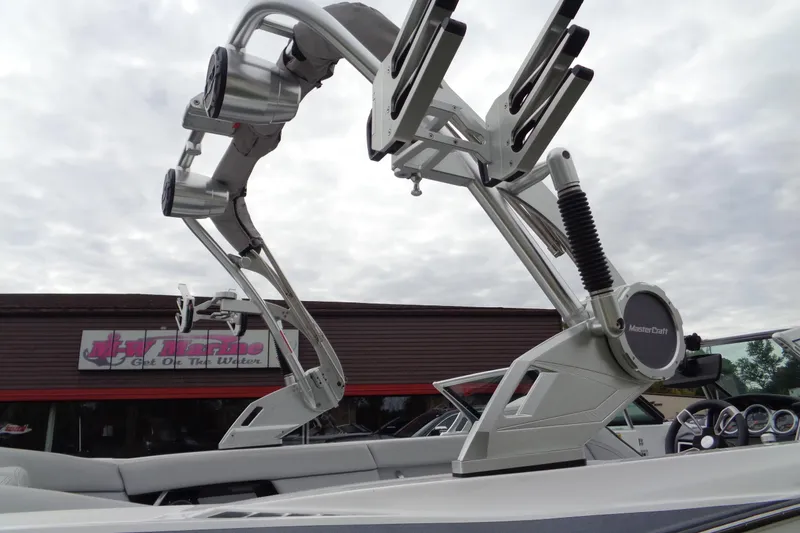Slide: The Image of 2020 MasterCraft XT23 boat with advanced wakeboard tower and speakers, displayed at a marine dealership. - 57