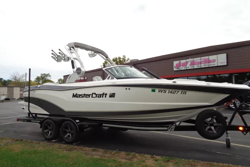 Slide: The Image of 2020 MasterCraft XT23 boat on trailer, parked outside a marine dealership. - 60