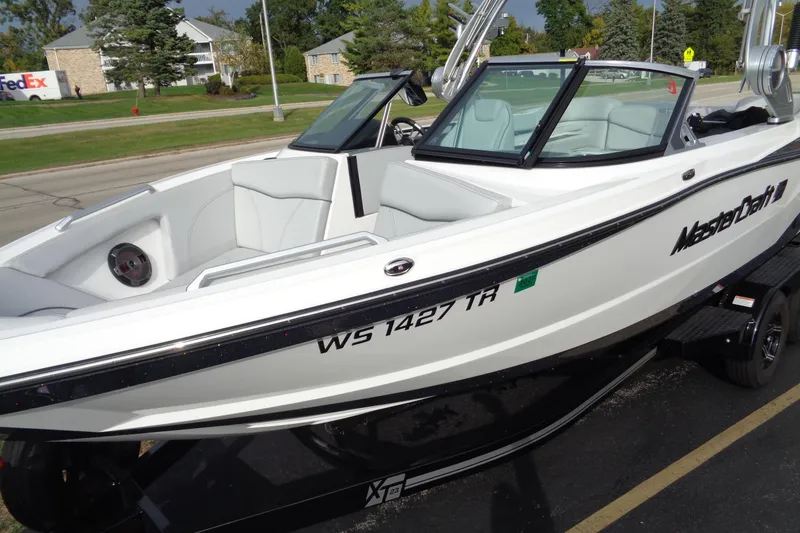 Slide: The Image of 2020 MasterCraft XT23 boat on trailer, white exterior, parked outdoors. - 64