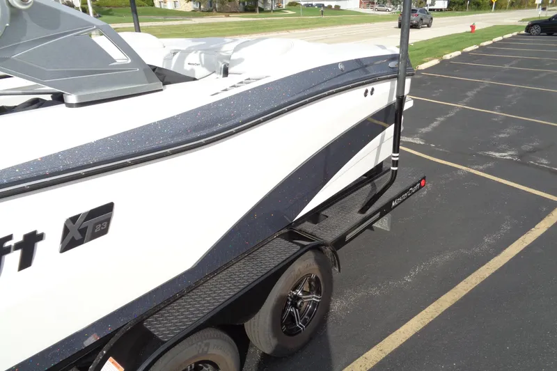 Slide: The Image of 2020 MasterCraft XT23 boat on trailer in parking lot, side view. - 66