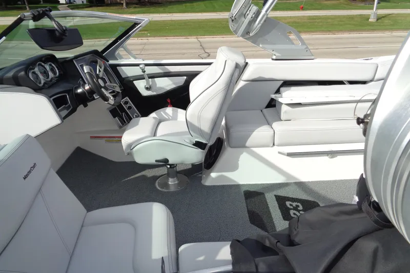 Slide: The Image of 2020 MasterCraft XT23 boat interior with sleek white seating and modern dashboard. - 67