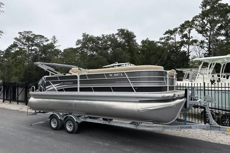 Slide: The Image of 2023 Godfrey Sweetwater 2286 C pontoon boat on trailer, parked outdoors. - 0