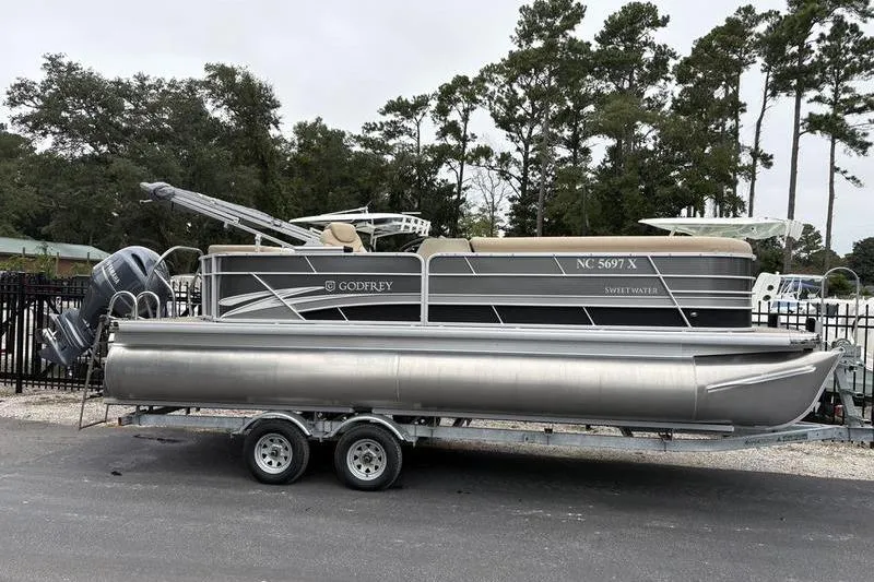 Slide: The Image of 2023 Godfrey Sweetwater 2286 C pontoon boat on trailer, parked outdoors. - 1