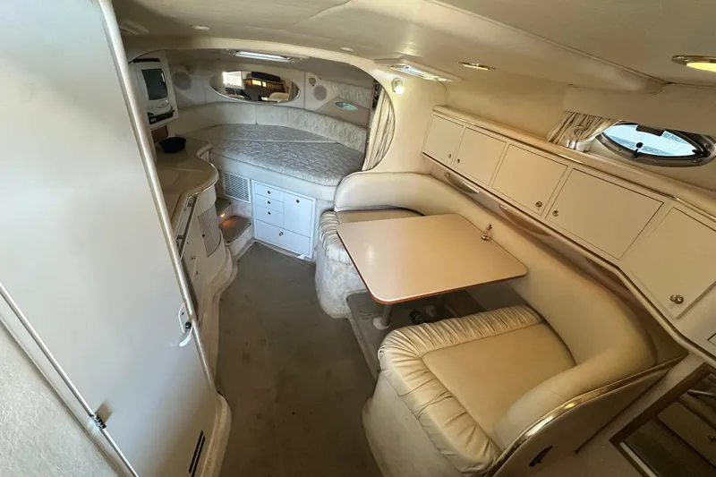 Slide: The Image of Interior of 2000 Sea Ray 310 Sundancer, featuring cozy seating and compact kitchenette. - 25