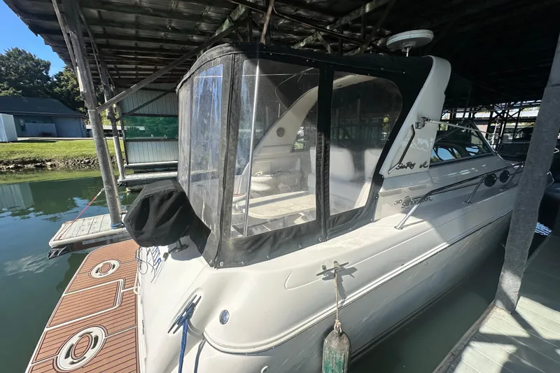 Slide: The Image of 2000 Sea Ray 310 Sundancer docked under a covered marina, featuring a clear enclosure. - 6