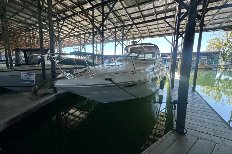 Slide: The Image of 2000 Sea Ray 310 Sundancer docked in a covered marina, reflecting on calm water. - 8