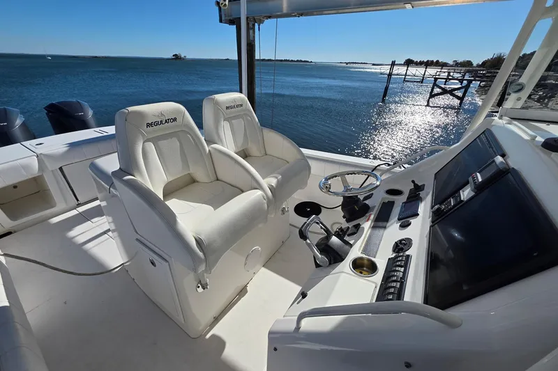 Slide: The Image of 2014 Regulator 34 boat cockpit with dual seats, steering wheel, and ocean view. - 10