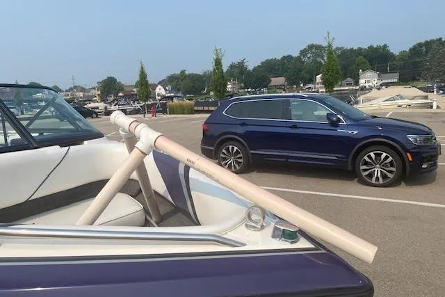 Slide: The Image of 1997 Malibu Echelon boat with PVC pipe support in a parking lot near a blue SUV. - 11