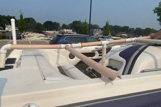 Slide: The Image of 1997 Malibu Echelon boat with custom PVC pipe modifications in a parking area. - 14
