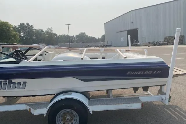 Slide: The Image of 1997 Malibu Echelon boat on trailer in parking lot near warehouse. - 15
