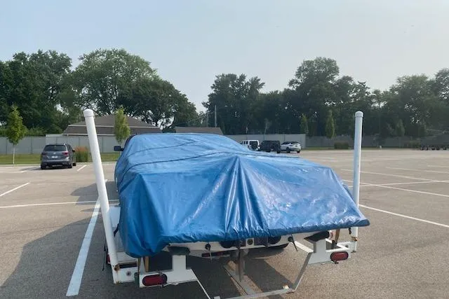 Slide: The Image of 1997 Malibu Echelon boat covered with blue tarp on trailer in parking lot. - 18