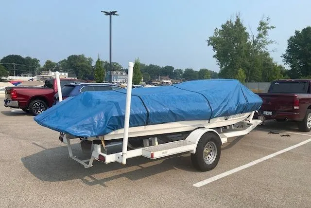 Slide: The Image of 1997 Malibu Echelon boat covered with blue tarp on trailer in parking lot. - 19