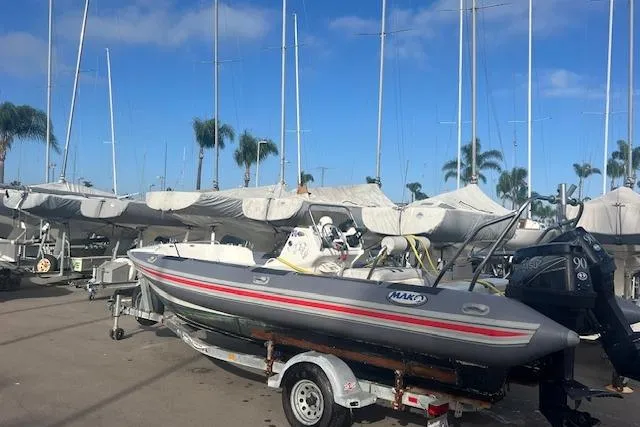 Slide: The Image of Hysucat 650 boat from 2001 on trailer, surrounded by sailboats and palm trees. - 7