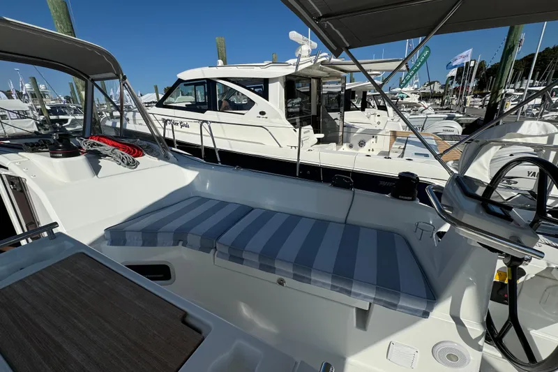 Slide: The Image of 2024 Beneteau Oceanis 37.1 sailboat cockpit with striped cushions, docked at marina. - 11
