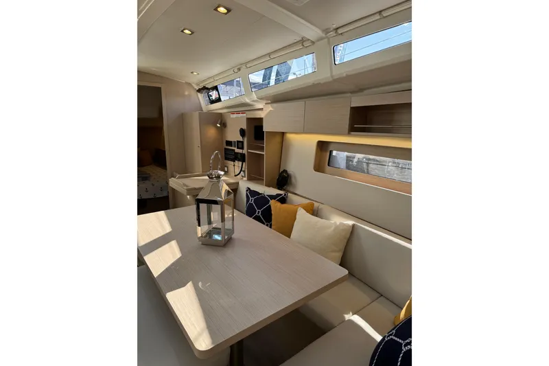 Slide: The Image of 2024 Beneteau Oceanis 37.1 interior with modern seating, table, and decorative pillows. - 27