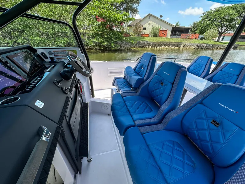 Slide: The Image of 2024 Axopar 37 Sun Top interior with blue seating and modern dashboard. - 3