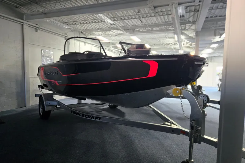 The Image of 2026 Princecraft Sport 175 boat on trailer in showroom, sleek black and red design. - 0