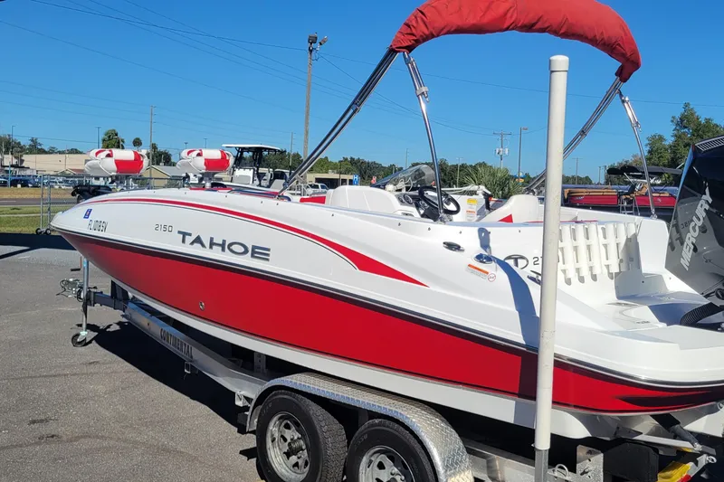 The Image of 2021 Tahoe 2150 boat with red and white design on a trailer, outdoor setting. - 0