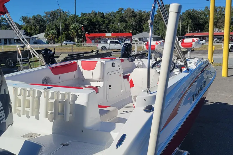 Slide: The Image of 2021 Tahoe 2150 boat with red and white interior, parked outdoors. - 2