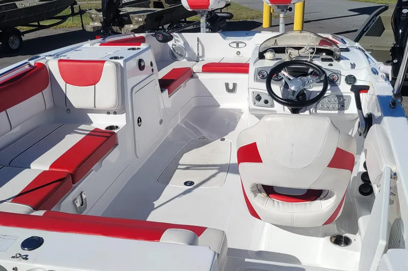 Slide: The Image of 2021 Tahoe 2150 boat interior with red and white seating, steering wheel, and control panel. - 4