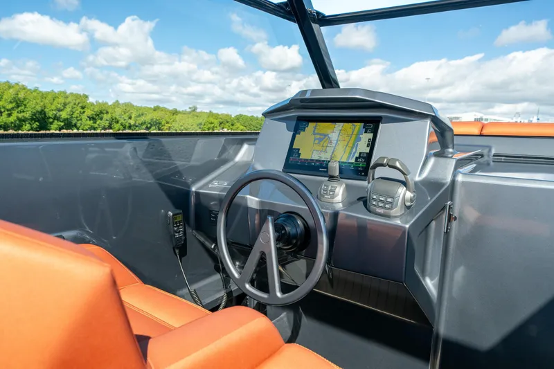 Slide: The Image of 2022 Vanquish Yachts VQ45 helm with navigation display and controls, featuring orange seating. - 6