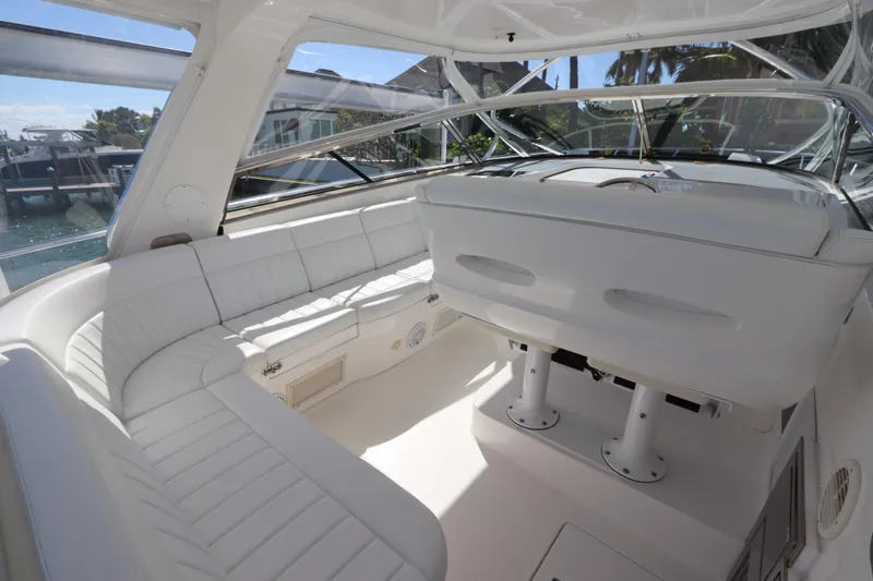 Slide: The Image of 2012 Intrepid 430 Sport Yacht interior with white seating and helm, docked by the water. - 26