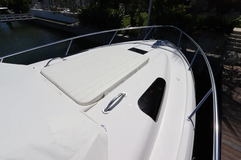 Slide: The Image of 2012 Intrepid 430 Sport Yacht deck with sunpad and railing, docked by water. - 7