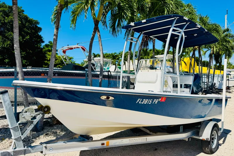 The Image of 2014 Frontier 180 boat on trailer, parked under palm trees, sunny day. - 0