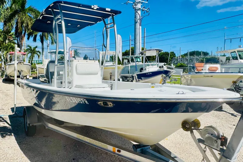 Slide: The Image of 2014 Frontier 180 boat on trailer, parked outdoors under clear blue sky. - 2