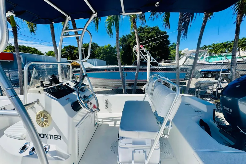 Slide: The Image of 2014 Frontier 180 boat interior with steering console and seating, parked outdoors. - 4