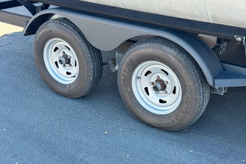 Slide: The Image of Trailer wheels of a 2024 Sun Tracker Fishin' Barge 20 DLX on asphalt. - 27
