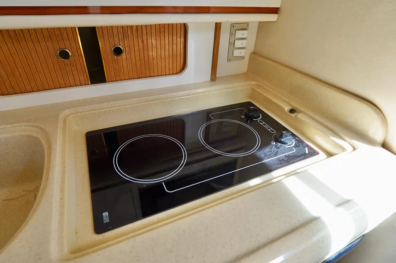 Slide: The Image of 2000 Sea Ray 280 Sundancer kitchen with electric stove and wooden cabinets. - 15