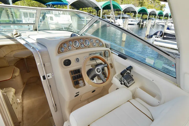 Slide: The Image of 2000 Sea Ray 280 Sundancer helm with gauges, steering wheel, and marina view. - 8