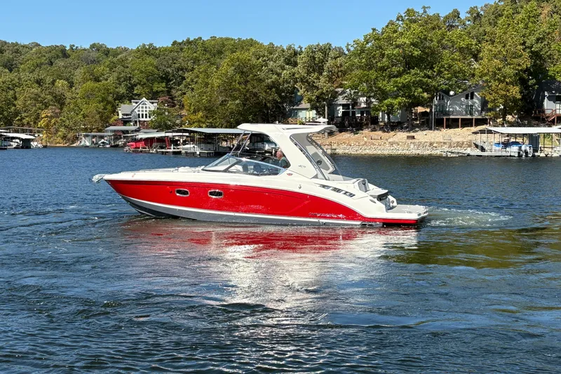 Slide: The Image of 2021 Chaparral 347 SSX boat cruising on a lake with scenic shoreline. - 2