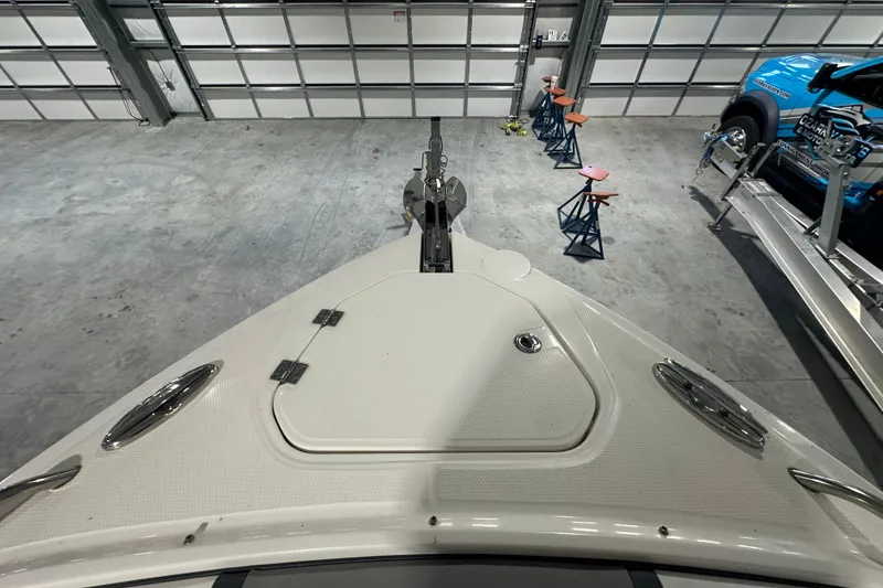 Slide: The Image of 2021 Chaparral 347 SSX boat bow in a garage, showcasing sleek design and storage hatch. - 29