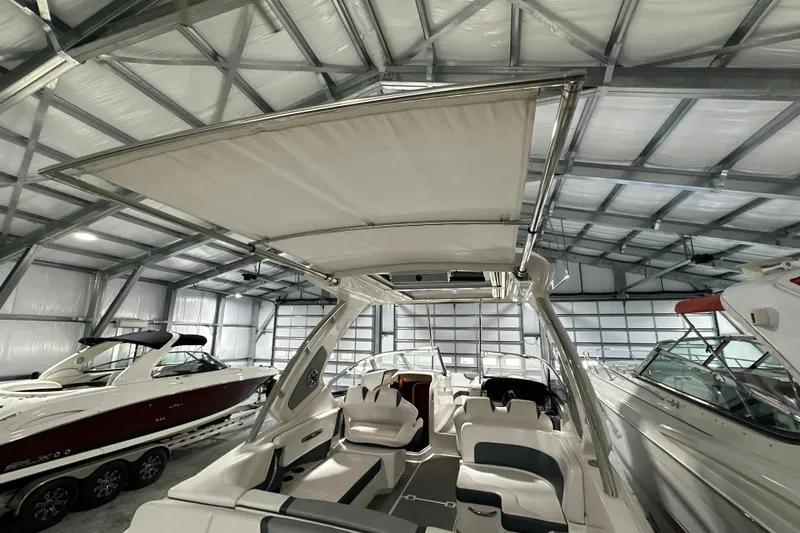 Slide: The Image of 2021 Chaparral 347 SSX boat in a storage facility, showcasing interior seating and canopy. - 47