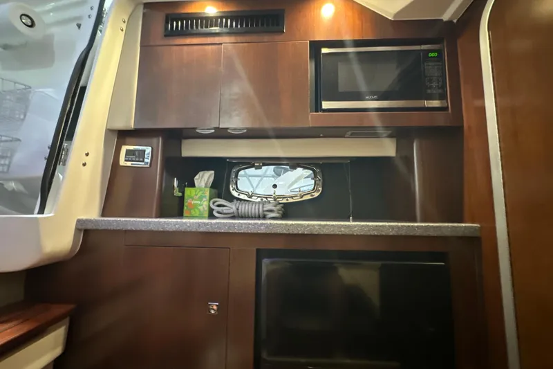 Slide: The Image of 2021 Chaparral 347 SSX boat interior with kitchenette, microwave, and storage cabinets. - 51