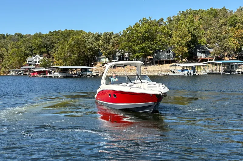 Slide: The Image of 2021 Chaparral 347 SSX boat cruising on a scenic lake with waterfront homes. - 6