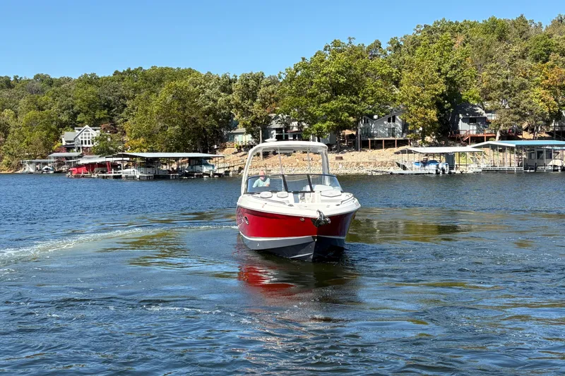 Slide: The Image of 2021 Chaparral 347 SSX boat cruising on a scenic lake with waterfront homes. - 7